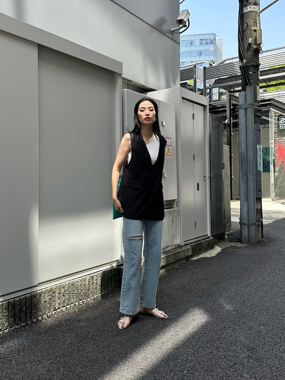 ブルー系のデニムパンツ、シルバー系のサンダル、グリーン系のトートバッグを着用したレディースの春コーディネートの2枚目の写真