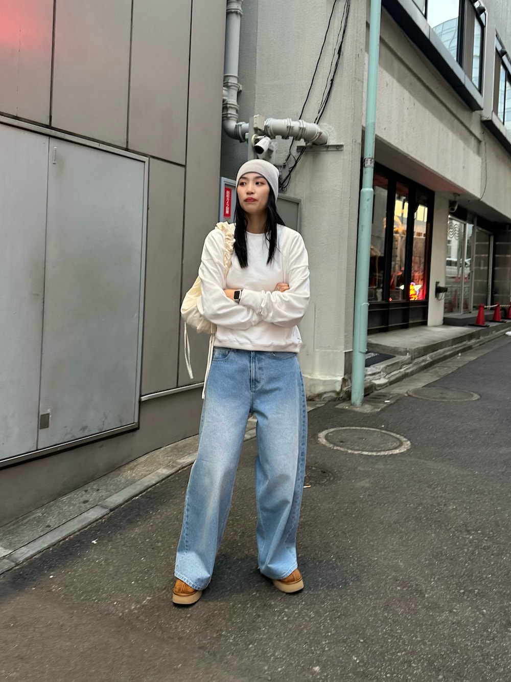 ホワイト系のショルダーバッグ、ブルー系のデニムパンツ、ホワイト系のスウェットを着用したレディースの冬コーディネートの2枚目の写真