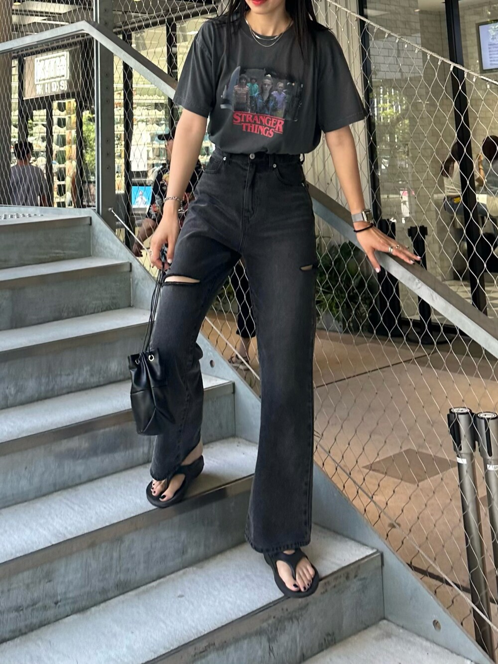 ブラック系のデニムパンツ、ブラック系のショルダーバッグ、シルバー系のネックレスを着用したレディースの夏コーディネートの2枚目の写真