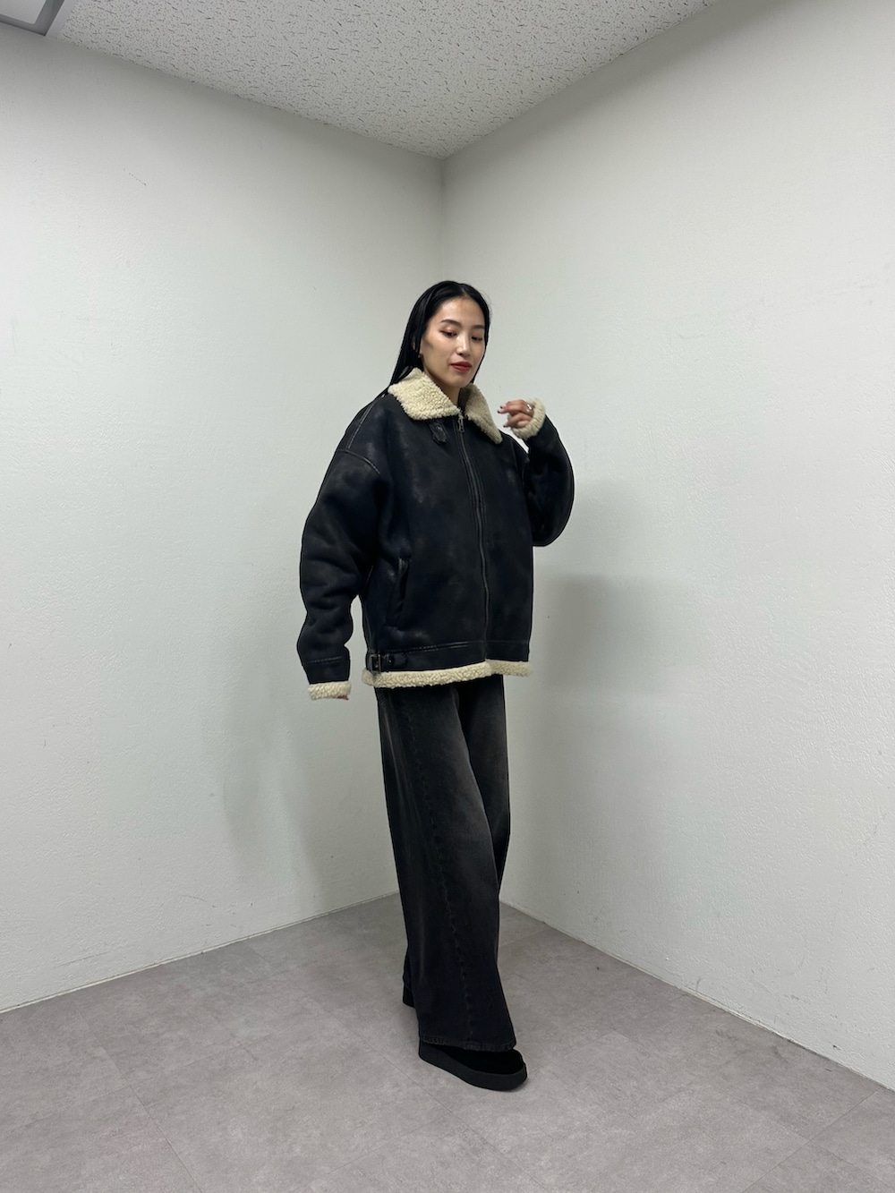 ブラック系のムートンコート、ブラック系のデニムパンツ、ブラック系のモカシン/デッキシューズを着用したレディースの秋コーディネートの2枚目の写真