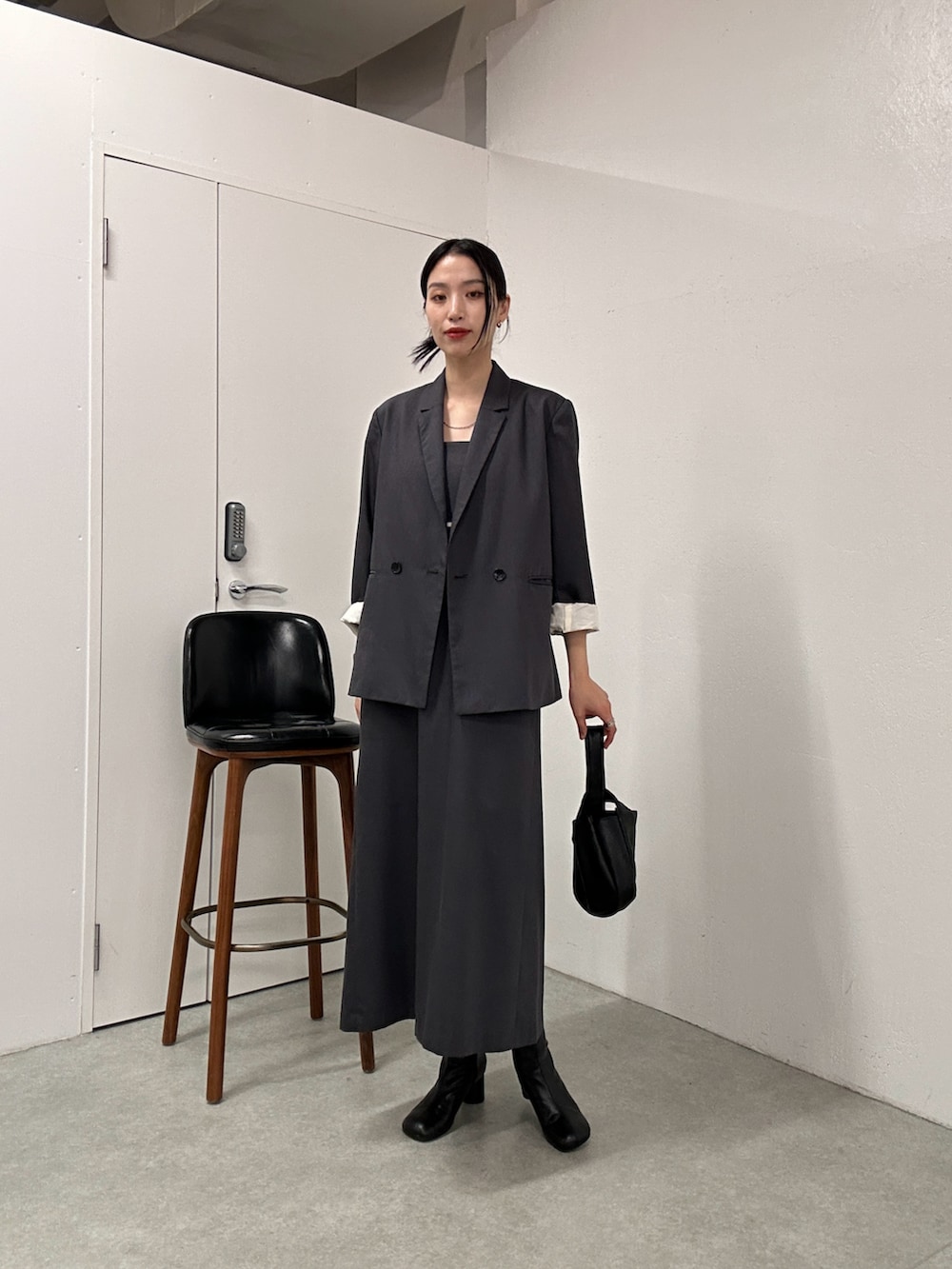 グレー系のテーラードジャケット、グレー系のドレス、ブラック系のハンドバッグを着用したレディースの冬コーディネートの4枚目の写真
