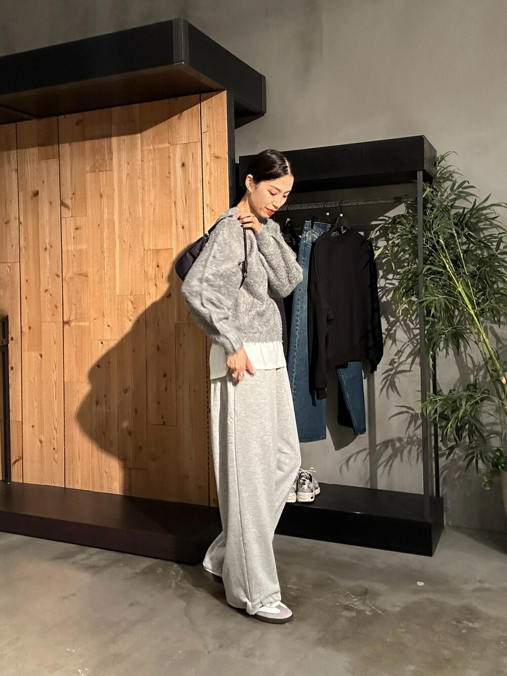グレー系のスウェットパンツ、グレー系のニット/セーター、ブラック系のハンドバッグを着用したレディースの秋コーディネートの2枚目の写真