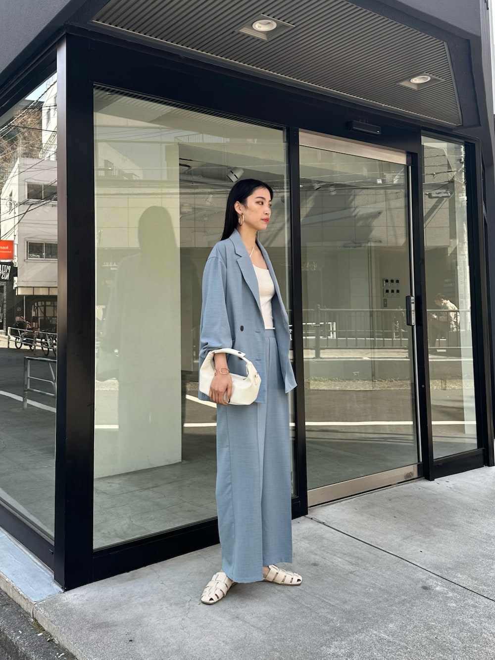 ブルー系のテーラードジャケット、ホワイト系のキャミソール、ブルー系のスラックスを着用したレディースの春コーディネートの2枚目の写真