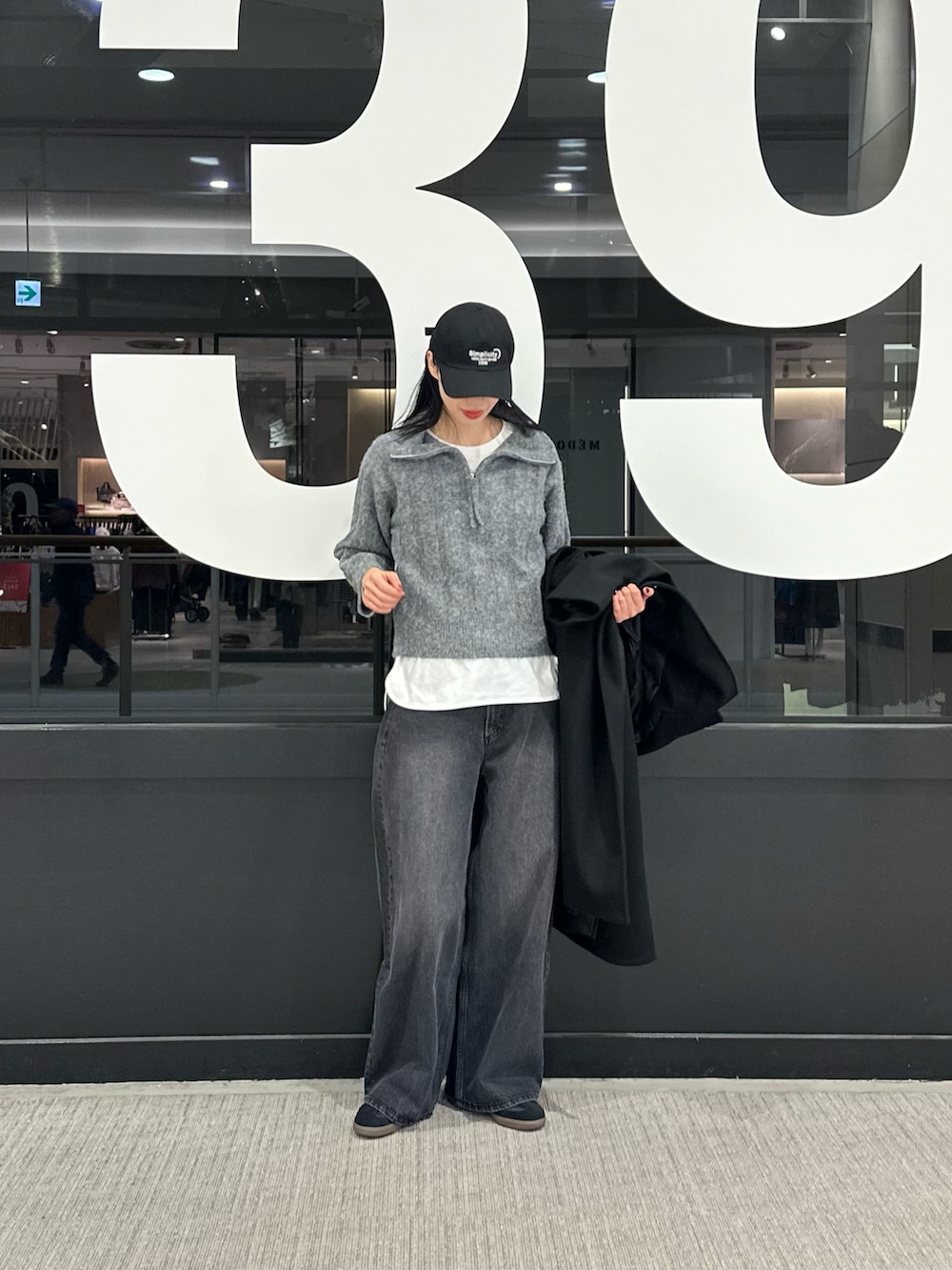 ブラック系のその他アウター、ホワイト系のTシャツ/カットソー、グレー系のニット/セーターを着用したレディースの冬コーディネートの4枚目の写真