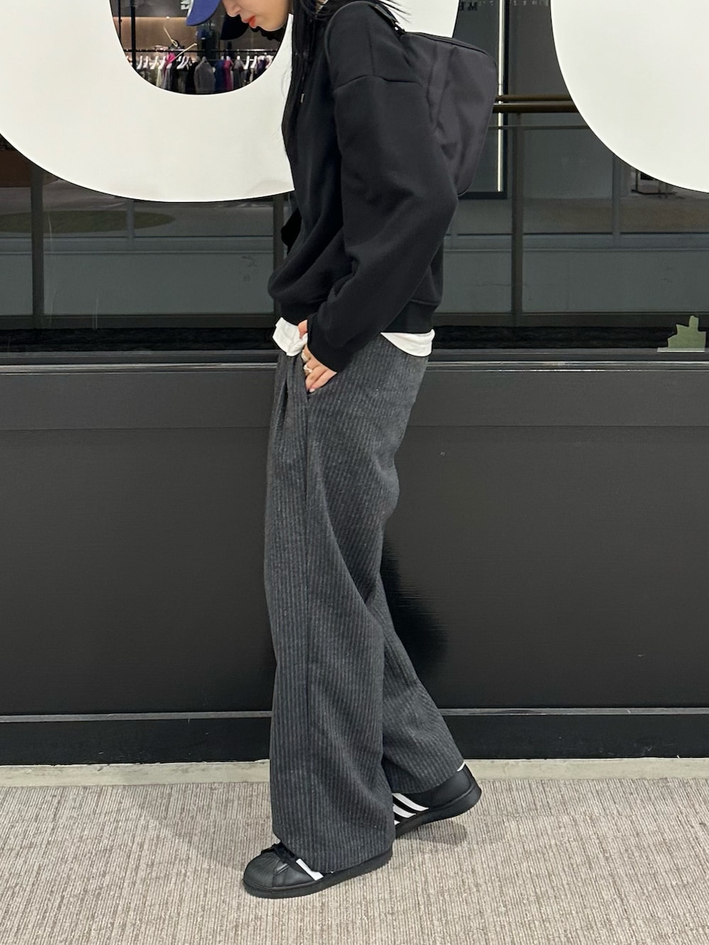 ブラック系のスウェット、ホワイト系のTシャツ/カットソー、グレー系のスラックスを着用したレディースの秋コーディネートの2枚目の写真