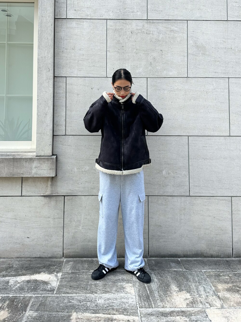 グレー系のカーゴパンツ、ブラック系のムートンコートを着用したレディースの秋コーディネートの2枚目の写真