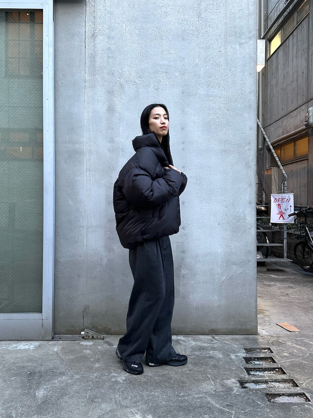 グレー系のスラックス、ブラック系のダウンジャケット/コート、グレー系のニット/セーターを着用したレディースの冬コーディネートの2枚目の写真