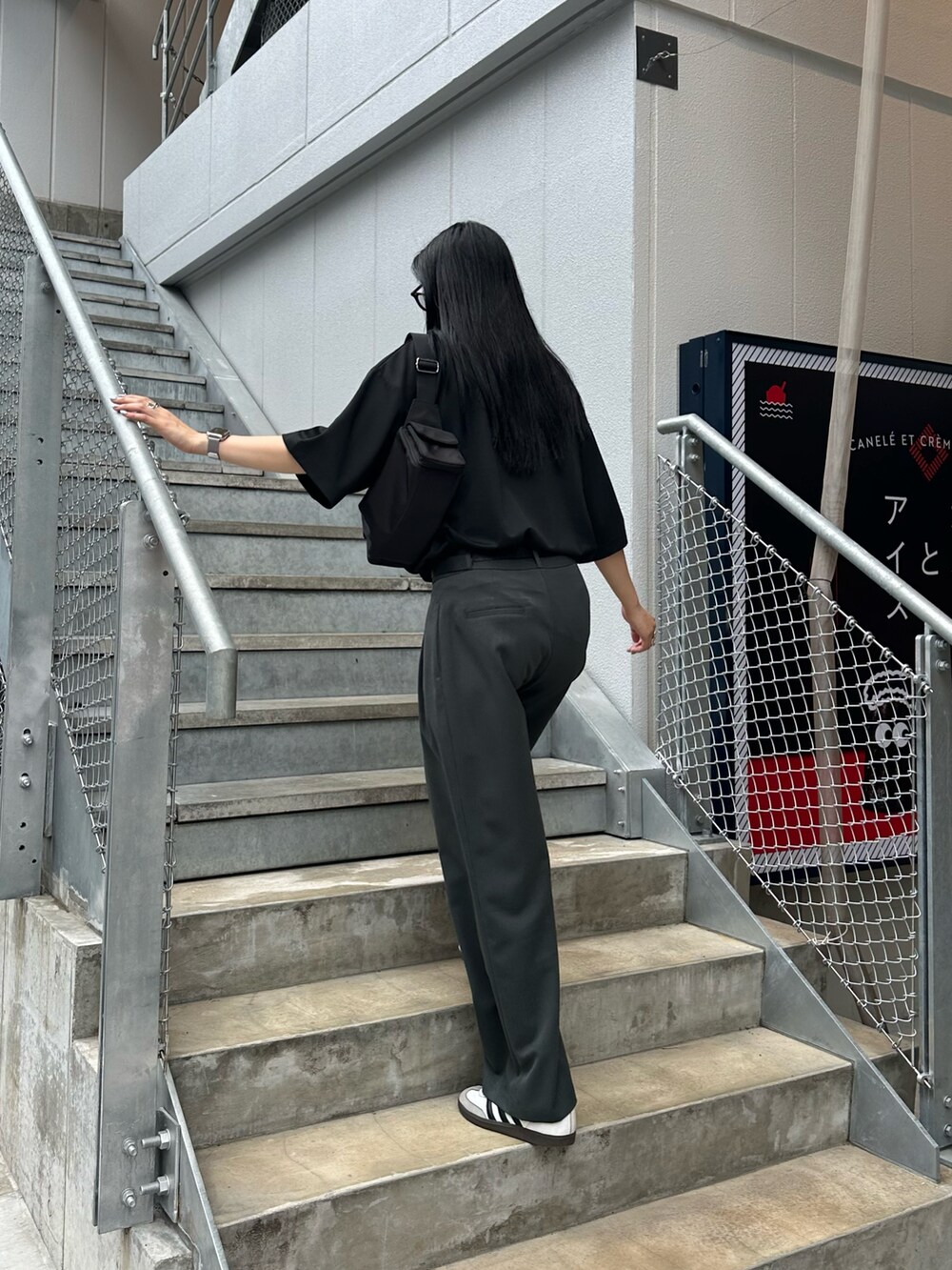 ブラック系のTシャツ/カットソー、ブラック系のショルダーバッグ、グレー系のスラックスを着用したレディースの夏コーディネートの4枚目の写真