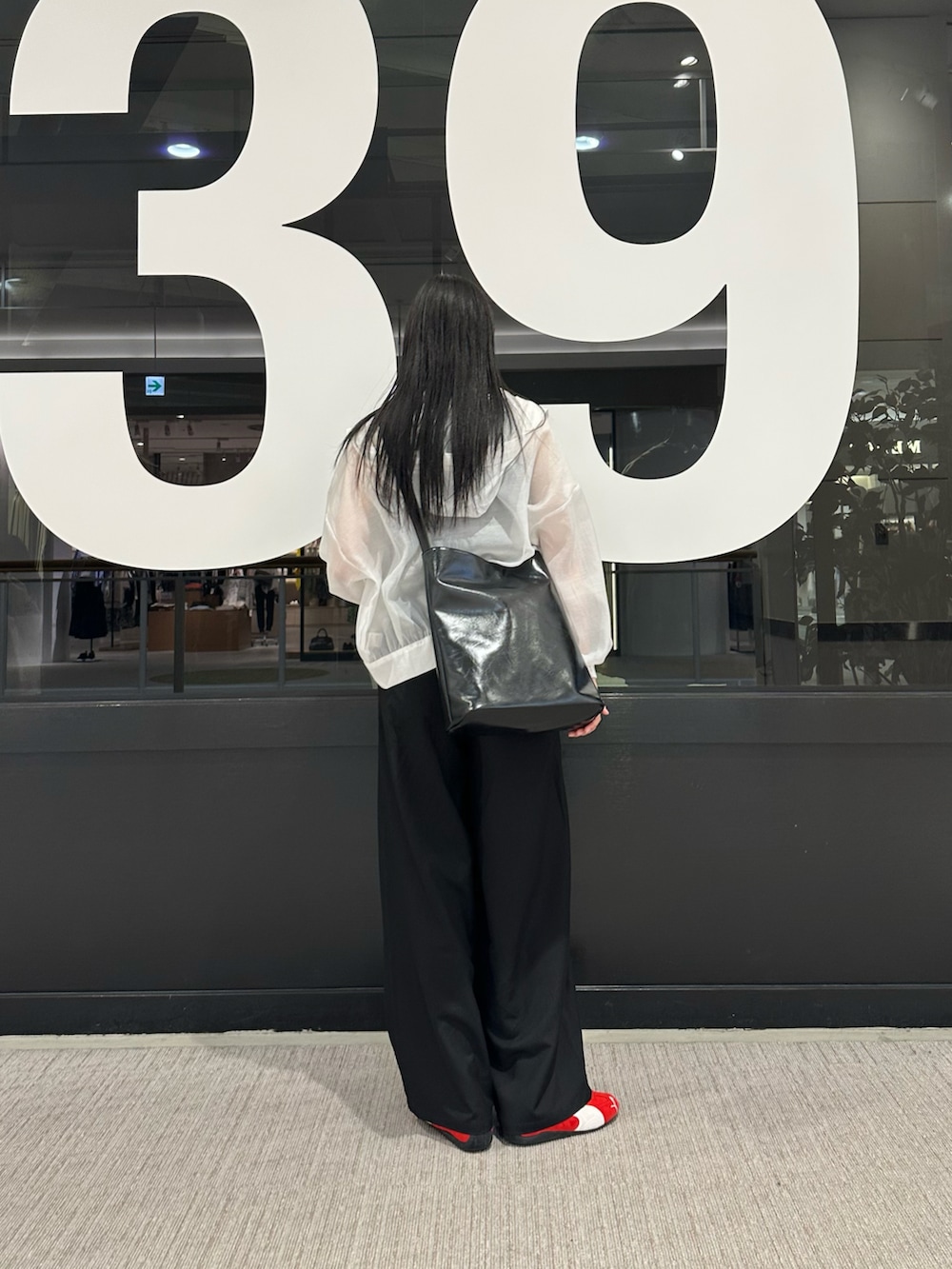 ホワイト系のマウンテンパーカー、ブラック系のタンクトップ、ブラック系のスラックスを着用したレディースの春コーディネートの3枚目の写真