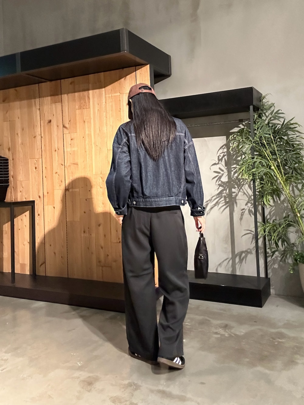 ブラック系のスラックス、ブルー系のデニムジャケット、ブラック系のハンドバッグを着用したレディースの秋コーディネートの3枚目の写真