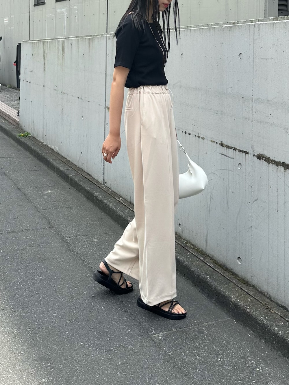 ホワイト系のショルダーバッグ、ベージュ系のその他パンツ、ブラック系のサンダルを着用したレディースの春コーディネートの2枚目の写真