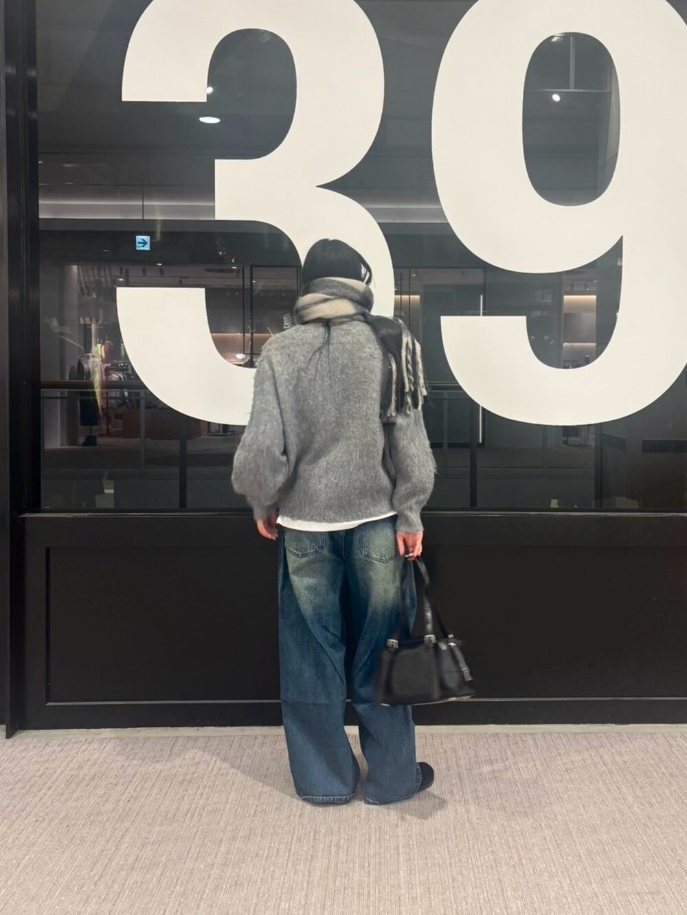 ブルー系のデニムパンツ、グレー系のカーディガン/ボレロ、ホワイト系のTシャツ/カットソーを着用したレディースの冬コーディネートの3枚目の写真