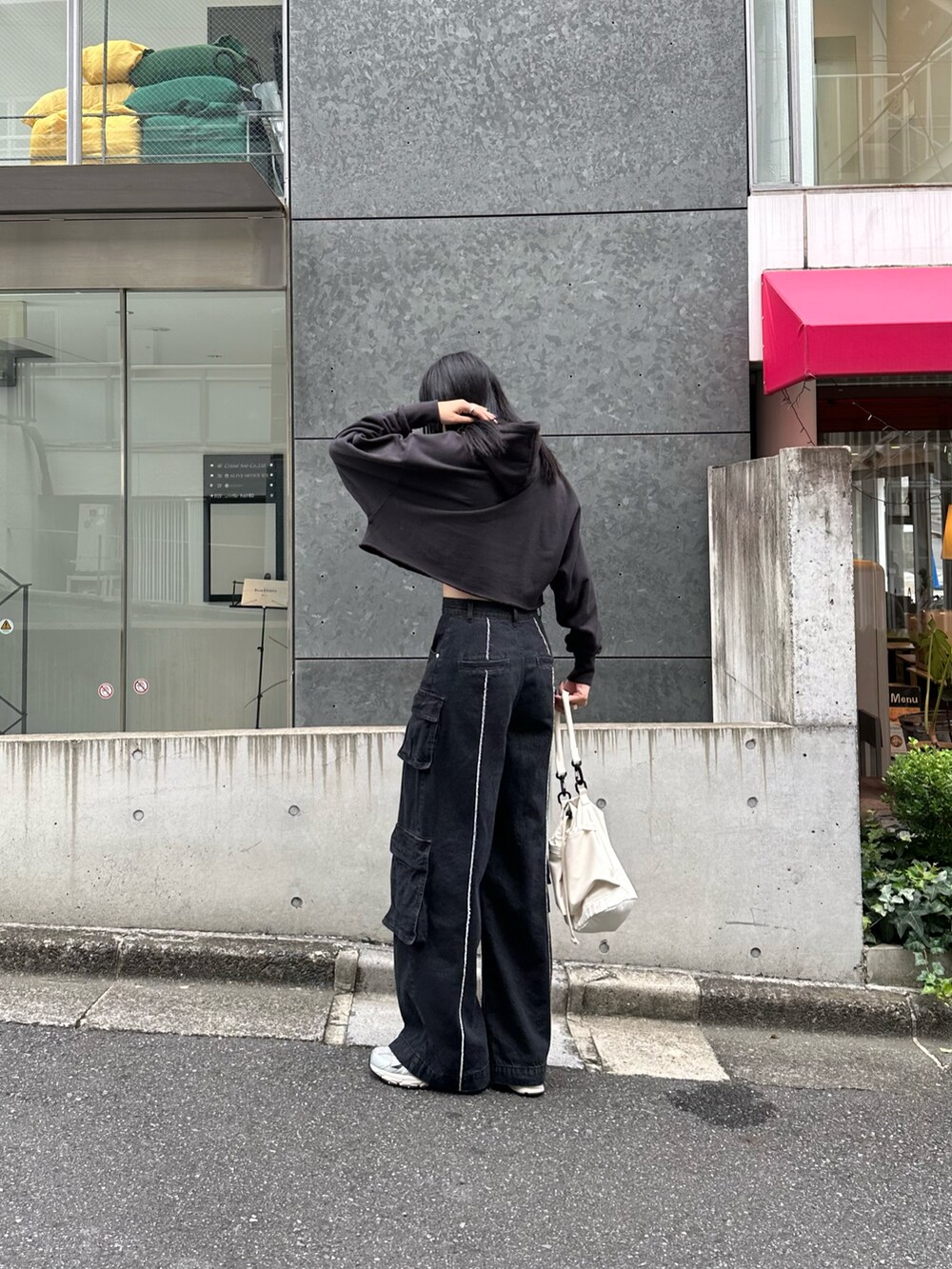 ブラック系のパーカー、ブラック系のデニムパンツ、ホワイト系のショルダーバッグを着用したレディースの秋コーディネートの3枚目の写真