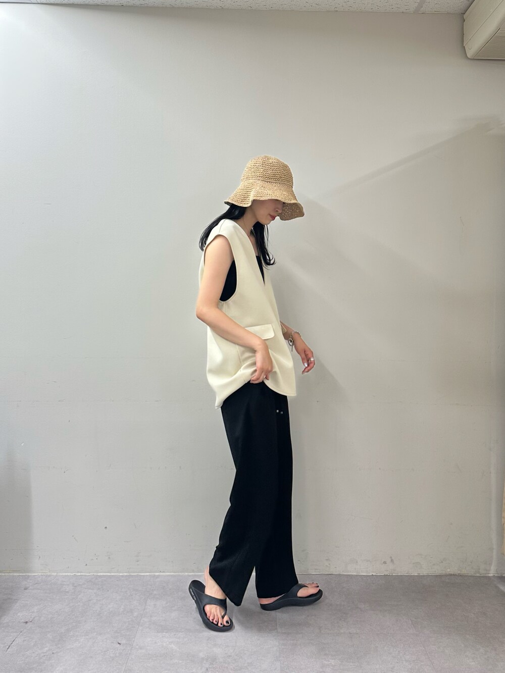 ブラック系のその他パンツ、ブラック系のサンダル、ホワイト系のベストを着用したレディースの春コーディネートの2枚目の写真