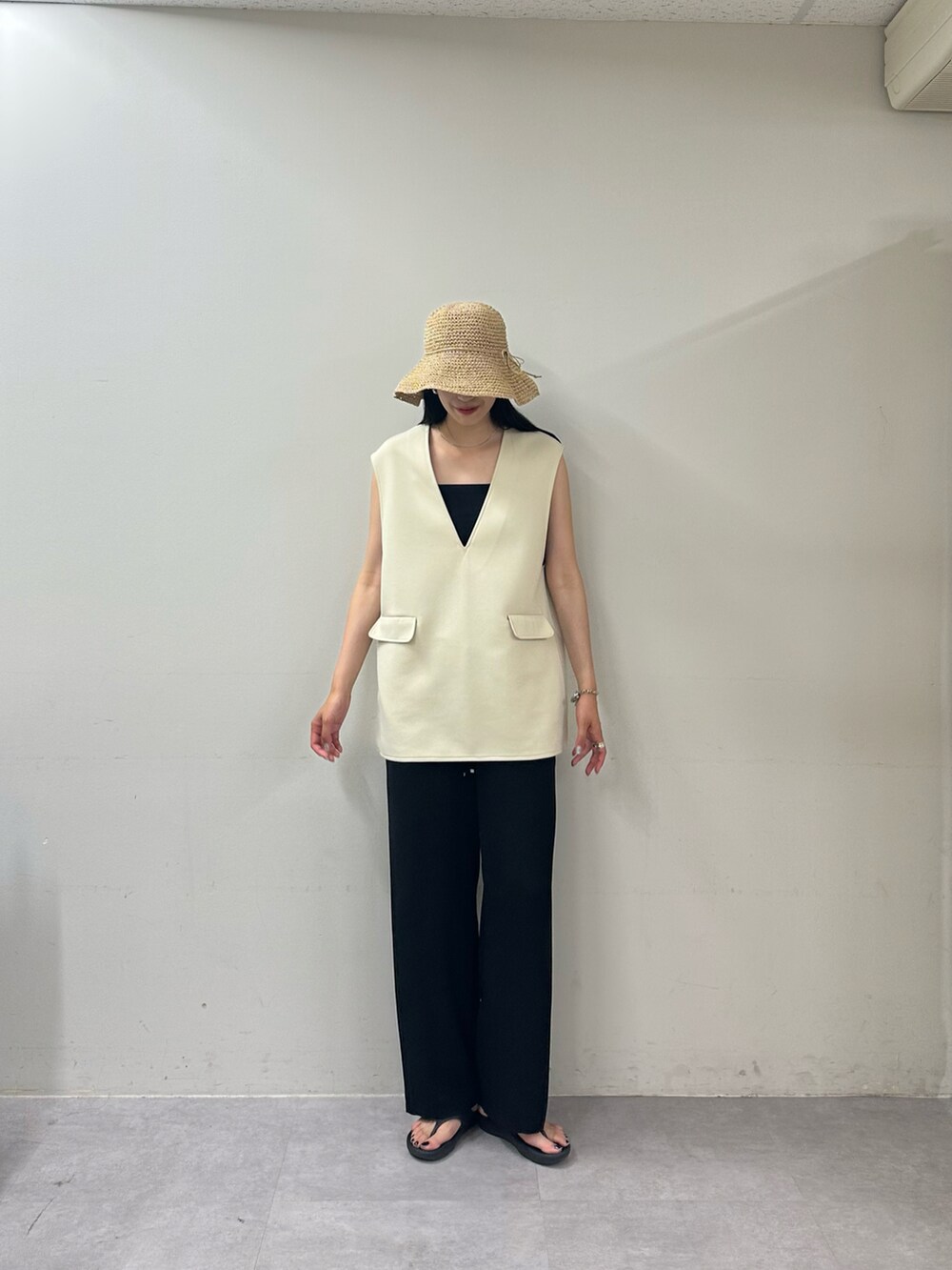 ブラック系のその他パンツ、ブラック系のサンダル、ホワイト系のベストを着用したレディースの春コーディネートの3枚目の写真