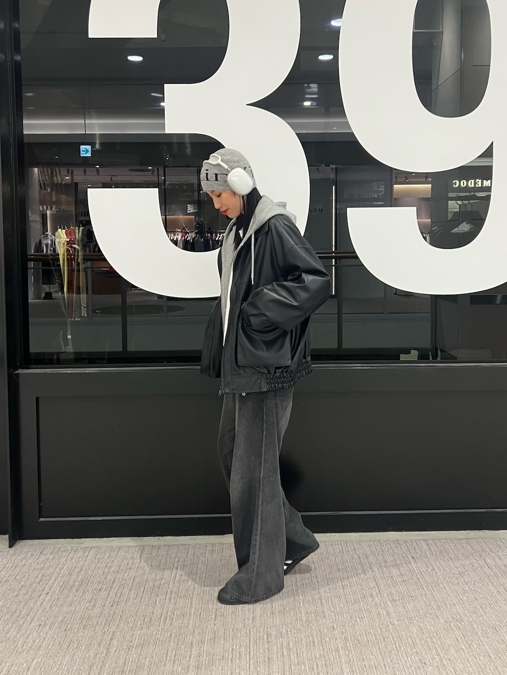 ブラック系のデニムパンツ、ブラック系のブルゾン、グレー系のパーカーを着用したレディースの秋コーディネートの2枚目の写真