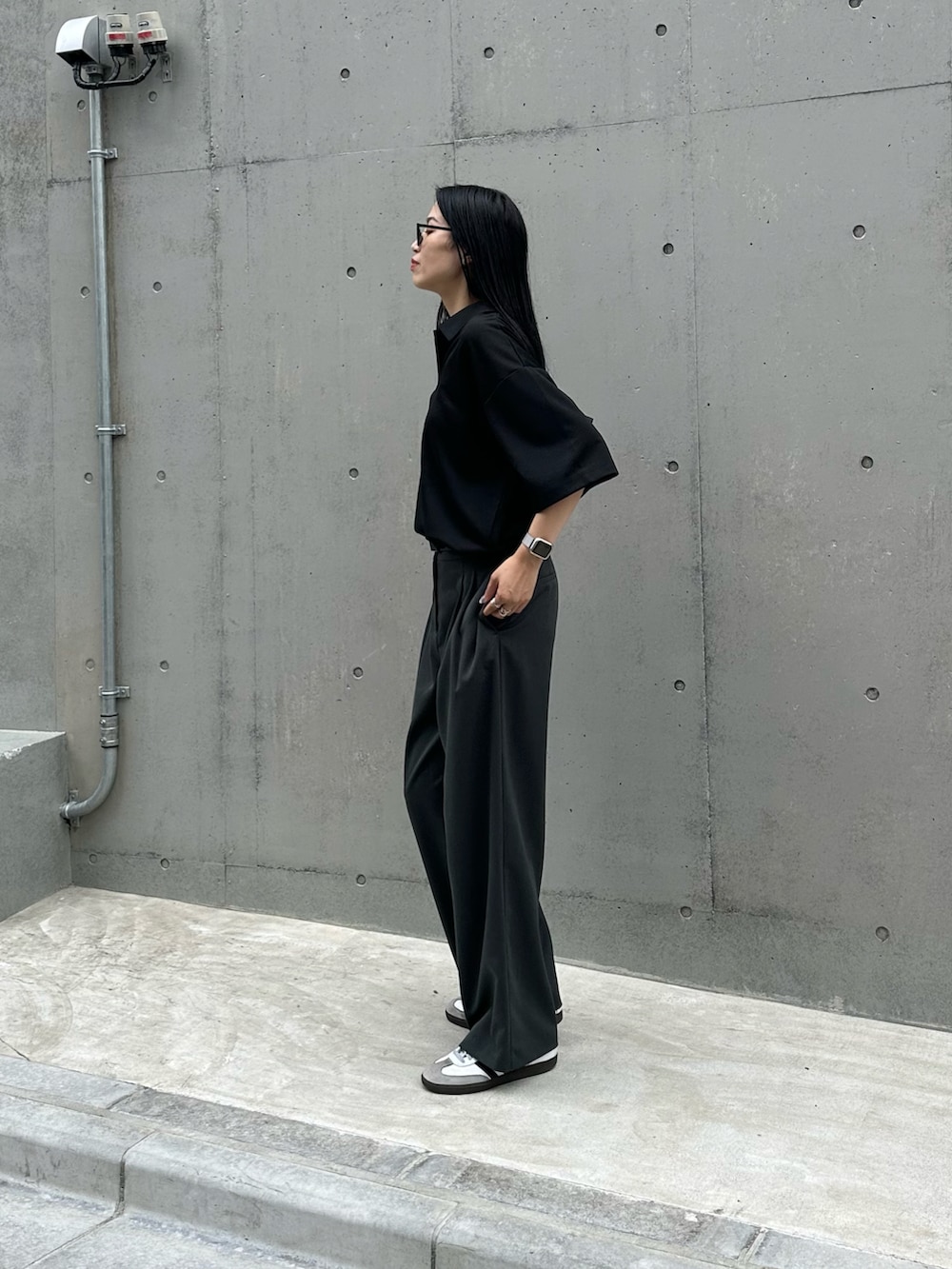 ブラック系のTシャツ/カットソー、ブラック系のショルダーバッグ、グレー系のスラックスを着用したレディースの夏コーディネートの2枚目の写真