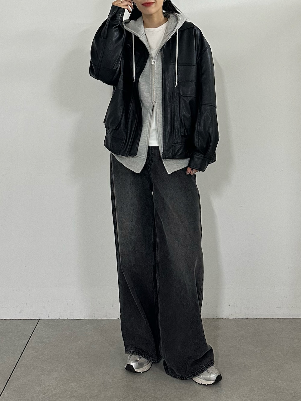 グレー系のパーカー、ブラック系のブルゾン、ブラック系のデニムパンツを着用したレディースの秋コーディネートの2枚目の写真