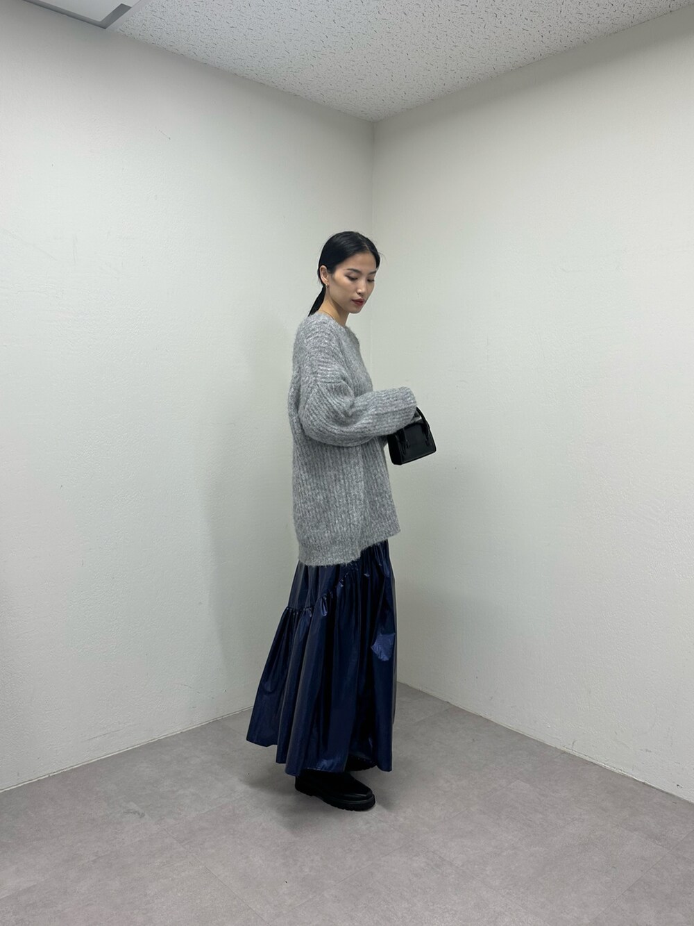 ブルー系のスカート、ブラック系のブーツ、ブラック系のショルダーバッグを着用したレディースの秋コーディネートの3枚目の写真