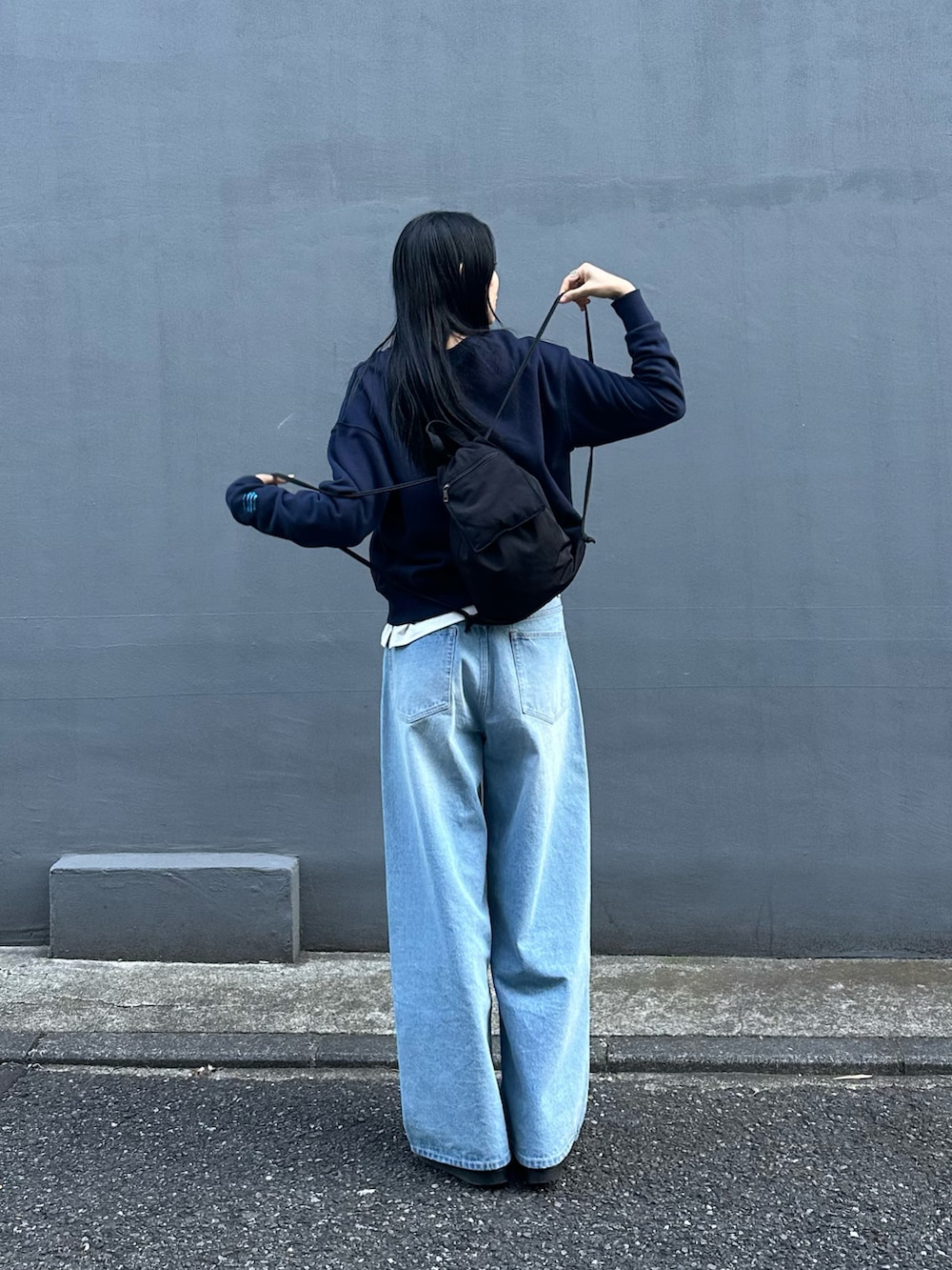 ブルー系のデニムパンツ、ブルー系のスウェット、ブラック系のバックパック/リュックを着用したレディースの冬コーディネートの3枚目の写真