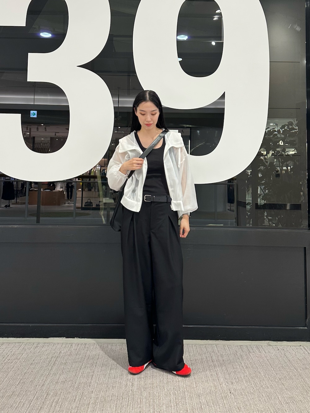 ホワイト系のマウンテンパーカー、ブラック系のタンクトップ、ブラック系のスラックスを着用したレディースの春コーディネートの4枚目の写真