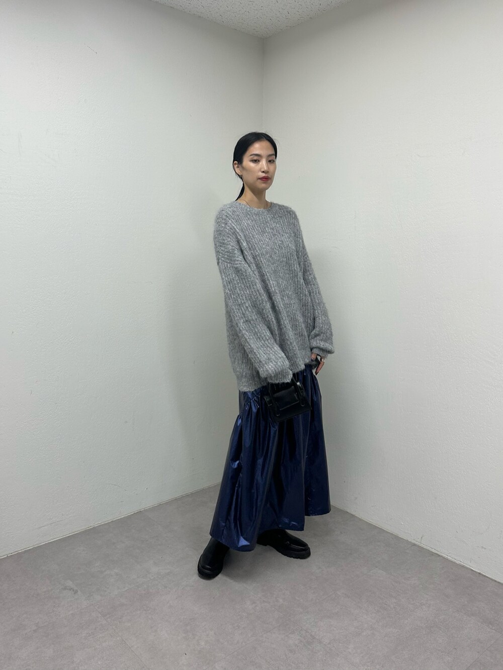 ブルー系のスカート、ブラック系のブーツ、ブラック系のショルダーバッグを着用したレディースの秋コーディネートの2枚目の写真