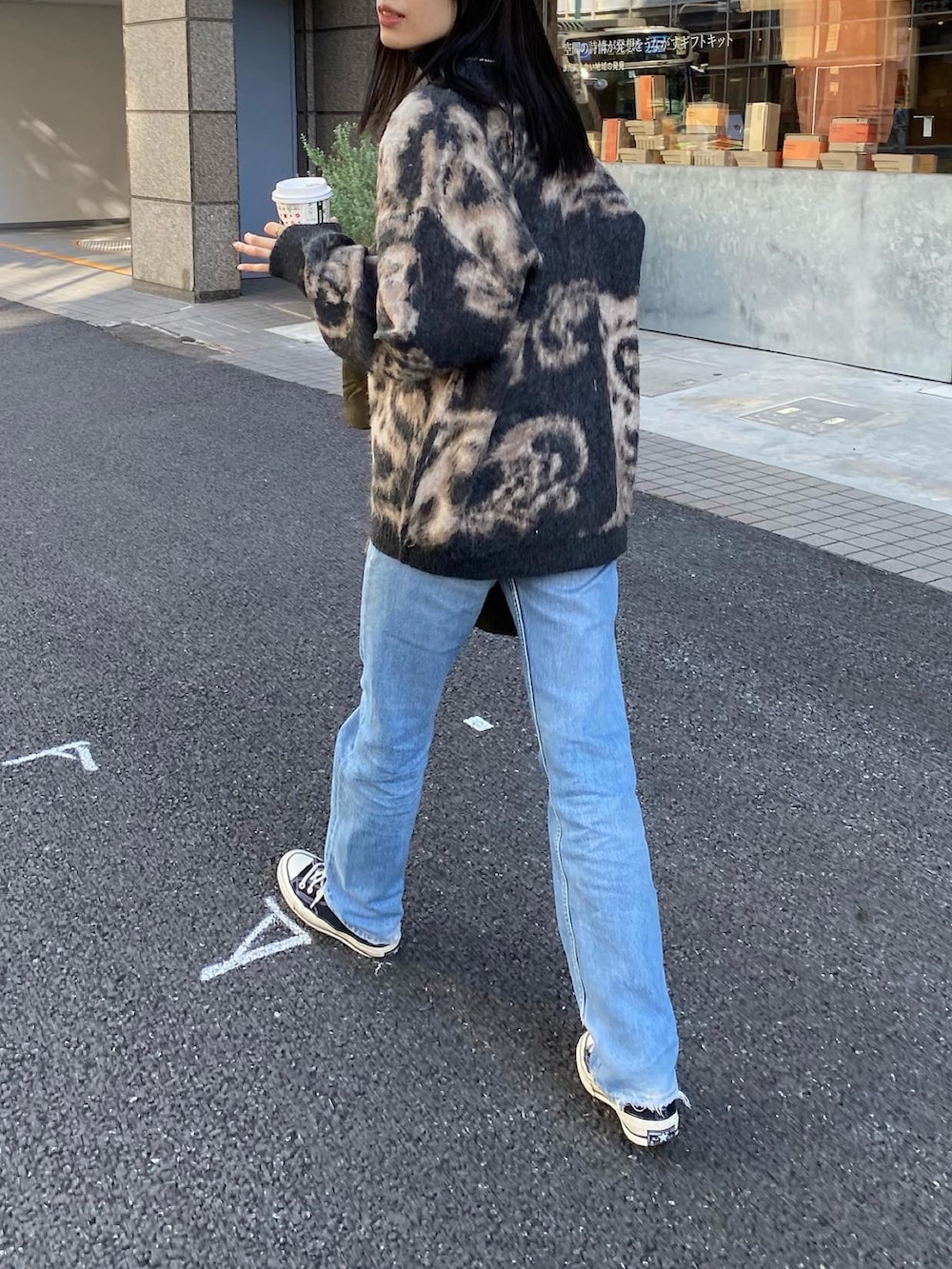 ブルー系のデニムパンツ、ブラック系のスニーカー、ブラック系のカーディガン/ボレロを着用したレディースの秋コーディネートの2枚目の写真