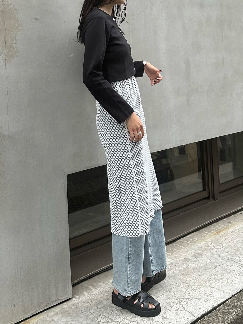ブラック系のサンダル、ブルー系のデニムパンツ、ホワイト系のスカートを着用したレディースの春コーディネートの2枚目の写真