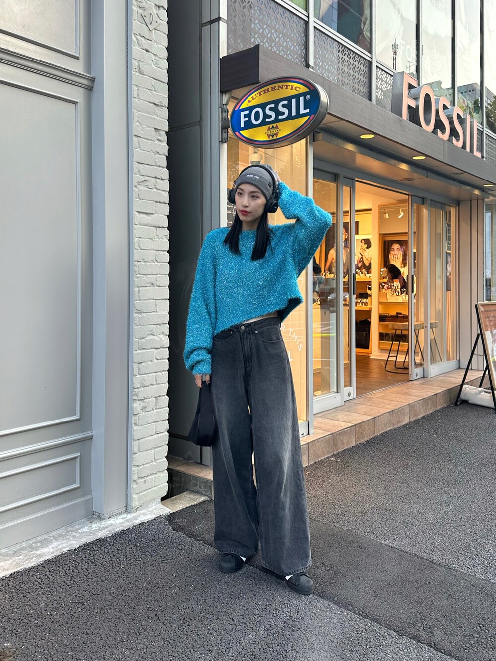 ブラック系のデニムパンツ、ブルー系のニット/セーター、グレー系のニットキャップ/ビーニーを着用したレディースの秋コーディネートの2枚目の写真