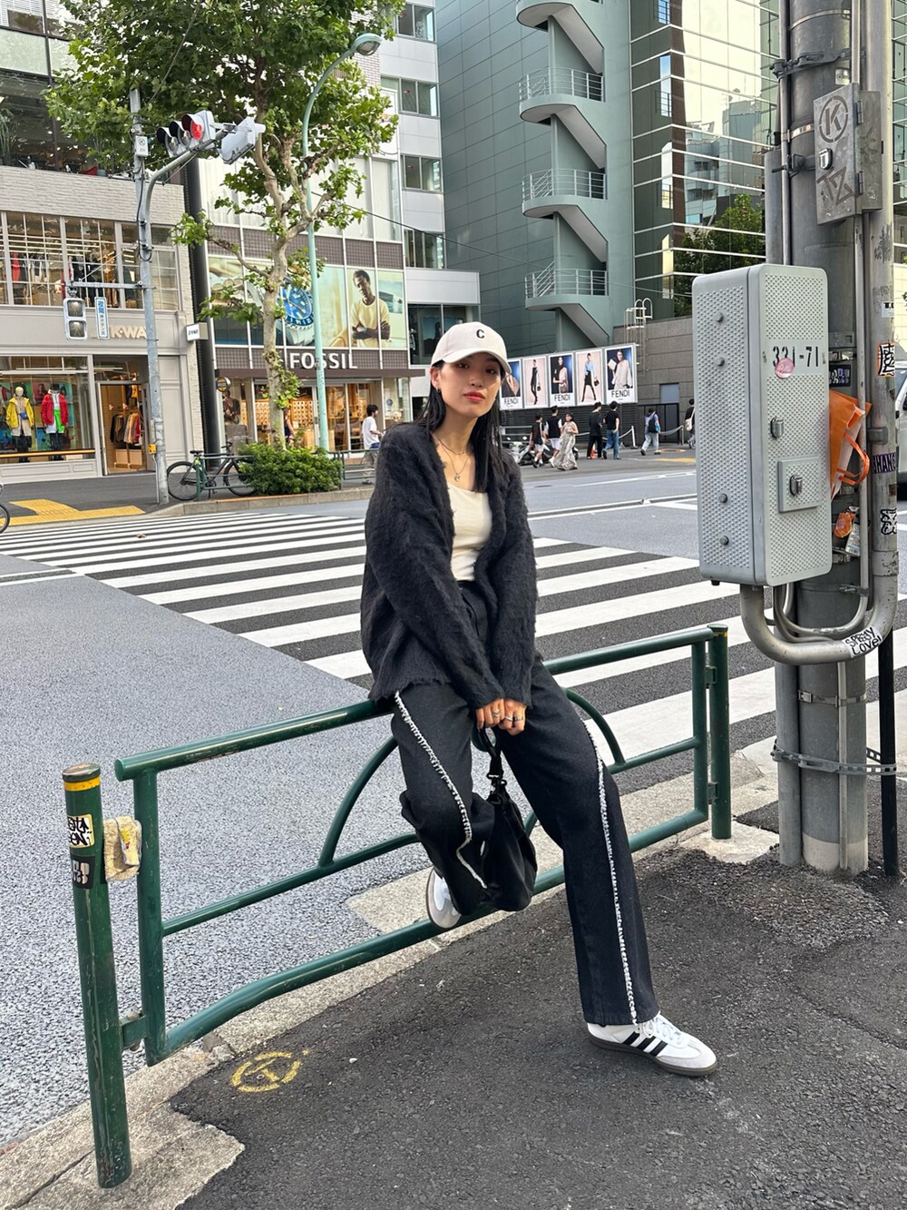 ブラック系のデニムパンツ、ブラック系のショルダーバッグ、ホワイト系のキャミソールを着用したレディースの秋コーディネートの2枚目の写真