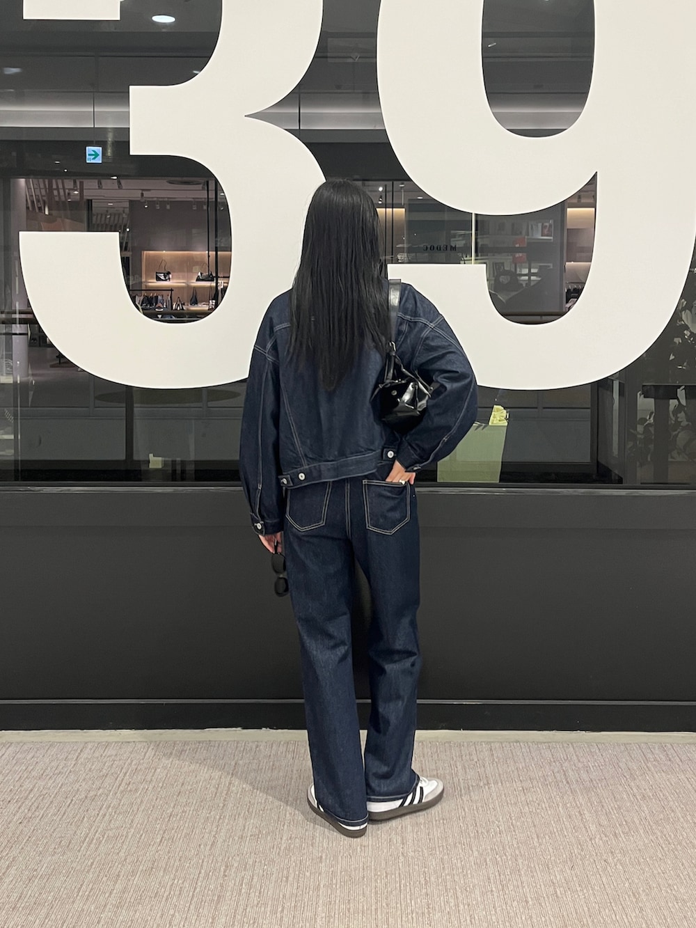 ブルー系のデニムパンツ、ブルー系のデニムジャケット、ホワイト系のタンクトップを着用したレディースの秋コーディネートの3枚目の写真