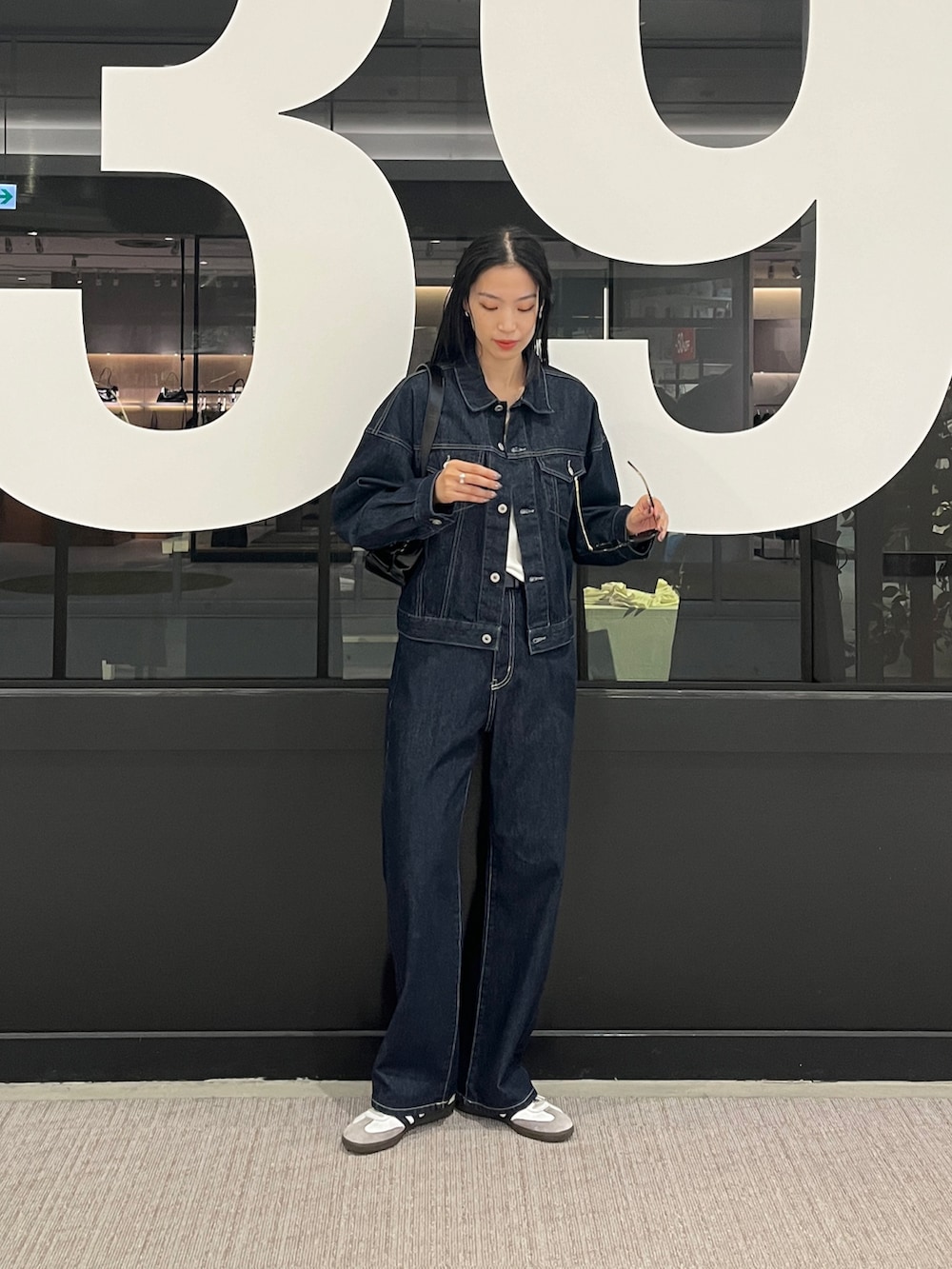 ブルー系のデニムパンツ、ブルー系のデニムジャケット、ホワイト系のタンクトップを着用したレディースの秋コーディネートの4枚目の写真