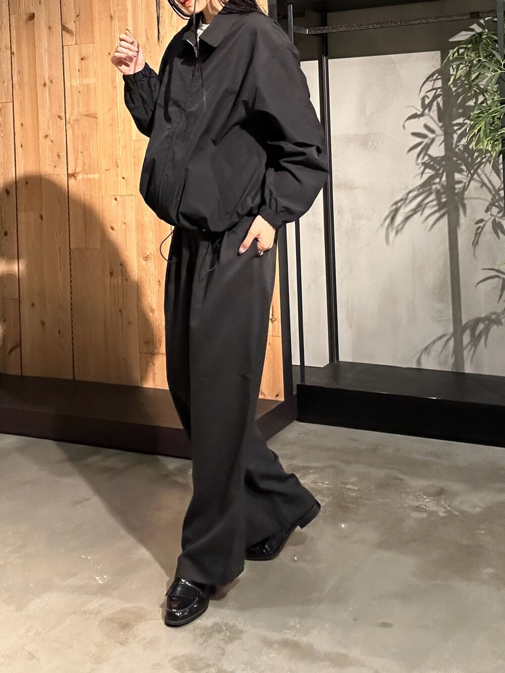 ブラック系のスラックス、ブラック系のブルゾン、ホワイト系のTシャツ/カットソーを着用したレディースの秋コーディネートの4枚目の写真