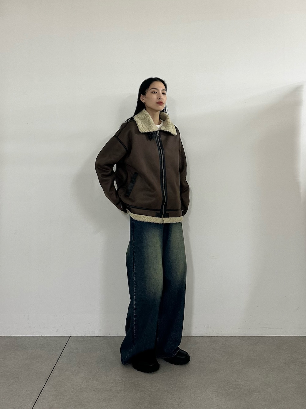 ブルー系のデニムパンツ、ブラウン系のムートンコート、ホワイト系のTシャツ/カットソーを着用したレディースの秋コーディネートの2枚目の写真