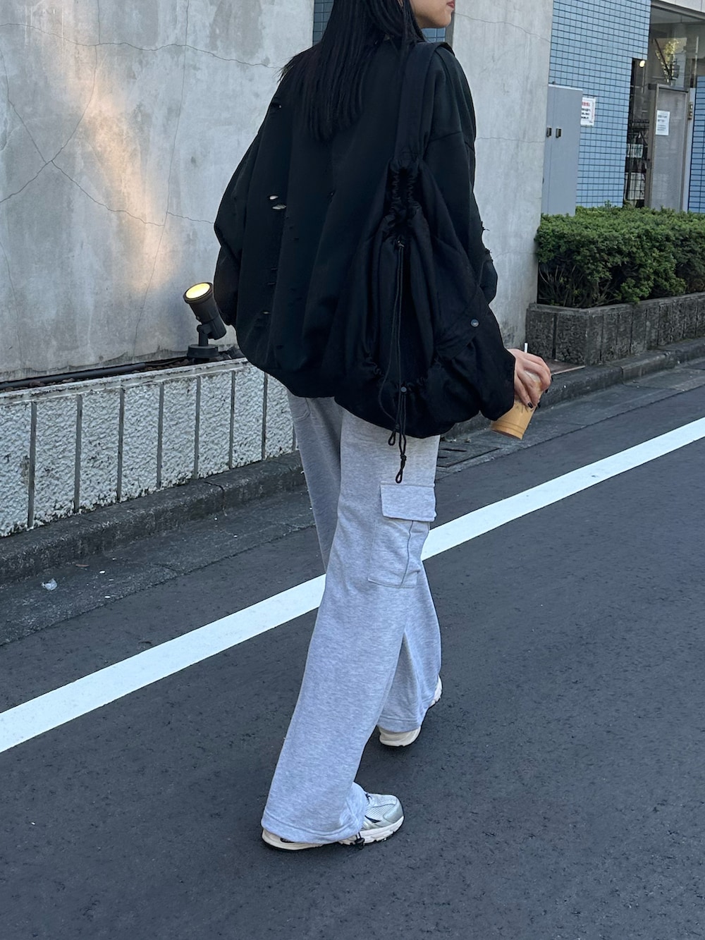 グレー系のカーゴパンツ、ブラック系のスウェット、ブラック系のショルダーバッグを着用したレディースの秋コーディネートの3枚目の写真