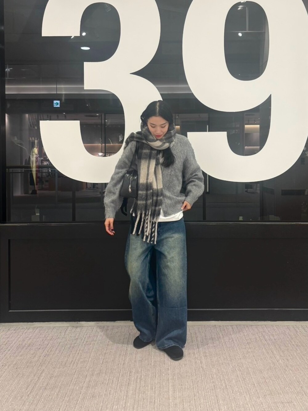 ブルー系のデニムパンツ、グレー系のカーディガン/ボレロ、ホワイト系のTシャツ/カットソーを着用したレディースの冬コーディネートの4枚目の写真