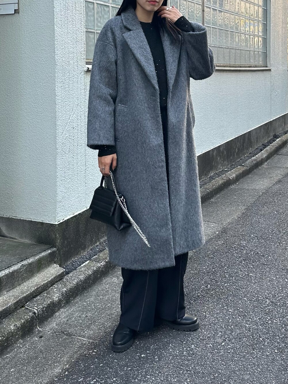 ブラック系のショルダーバッグ、グレー系のチェスターコート、ブラック系のニット/セーターを着用したレディースの秋コーディネートの2枚目の写真