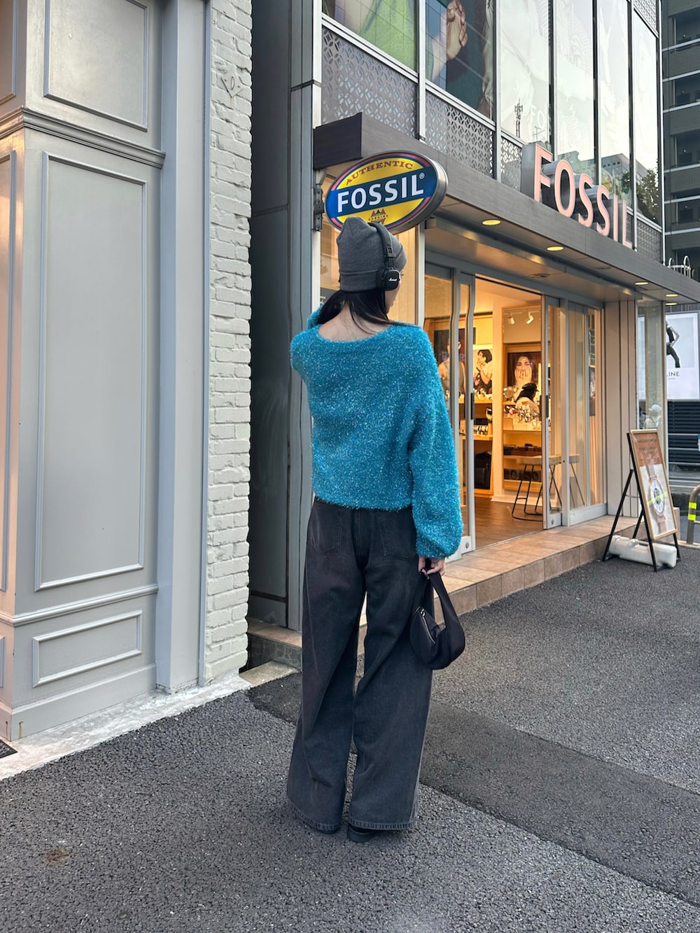 ブラック系のデニムパンツ、ブルー系のニット/セーター、グレー系のニットキャップ/ビーニーを着用したレディースの秋コーディネートの3枚目の写真