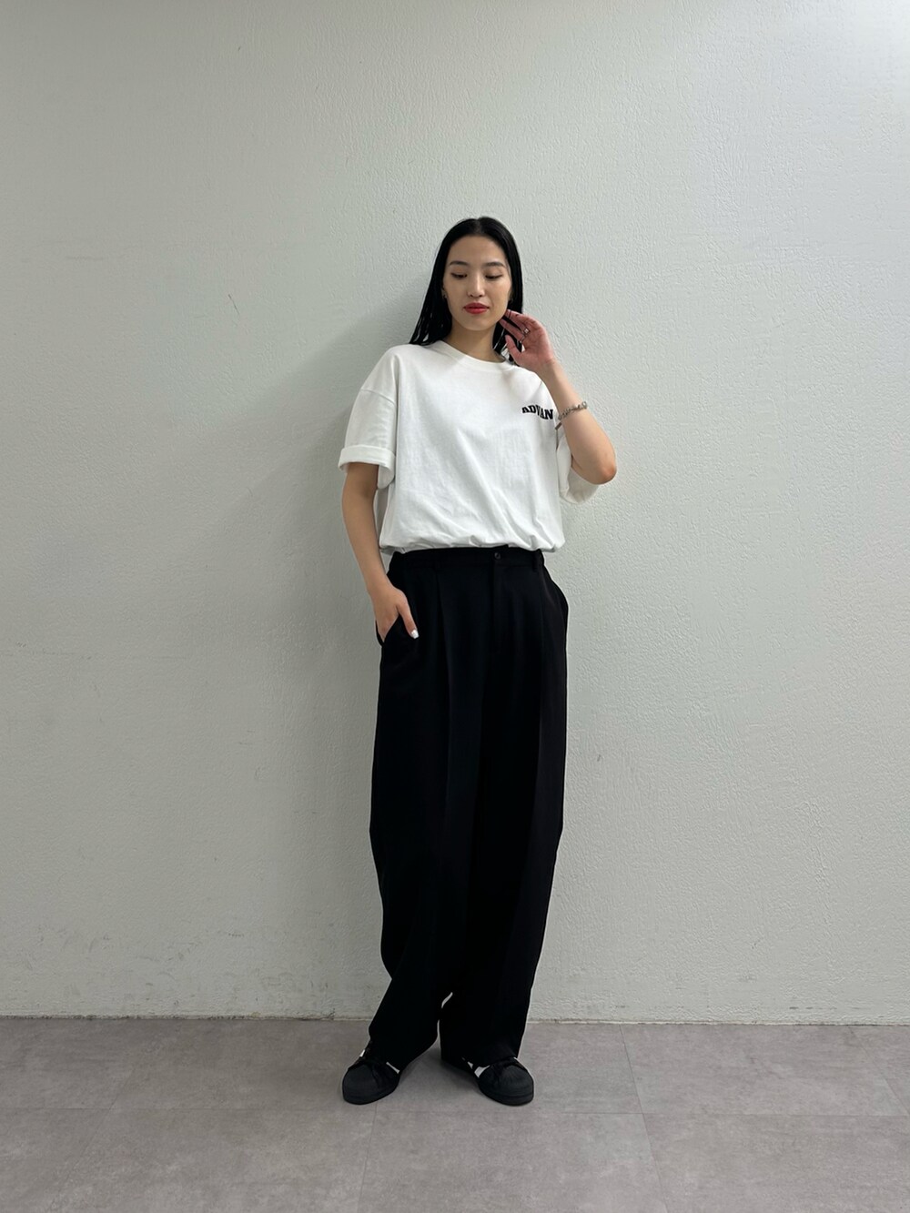 ブラック系のスラックス、ホワイト系のTシャツ/カットソーを着用したレディースの夏コーディネートの2枚目の写真