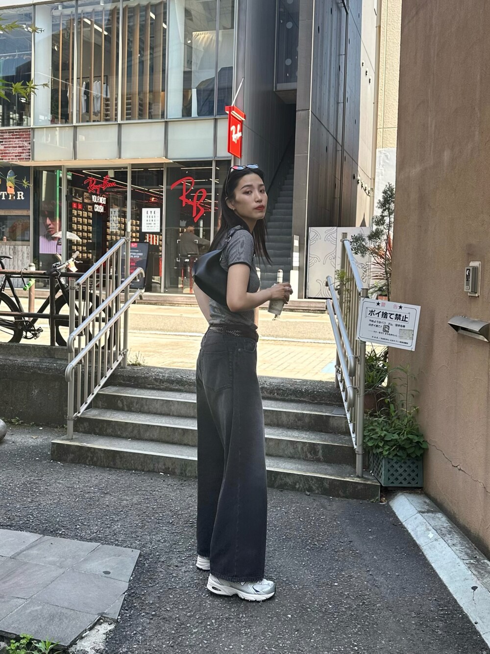 ブラック系のデニムパンツ、ブラック系のTシャツ/カットソー、ブラック系のショルダーバッグを着用したレディースの春コーディネートの3枚目の写真