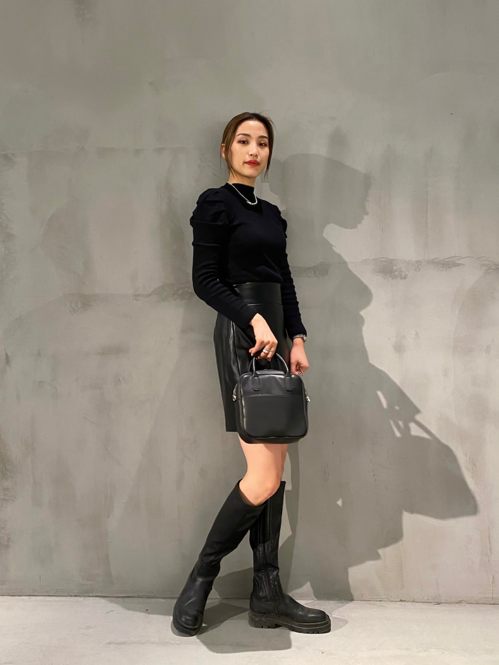ブラック系のスカート、ブラック系のボストンバッグ、ブラック系のブーツを着用したレディースの冬コーディネートの2枚目の写真