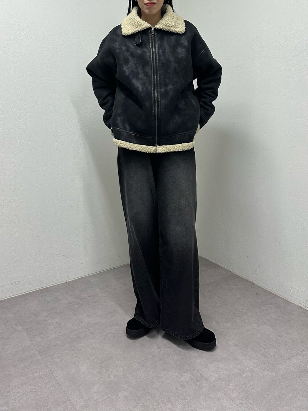 ブラック系のムートンコート、ブラック系のデニムパンツ、ブラック系のモカシン/デッキシューズを着用したレディースの秋コーディネートの3枚目の写真