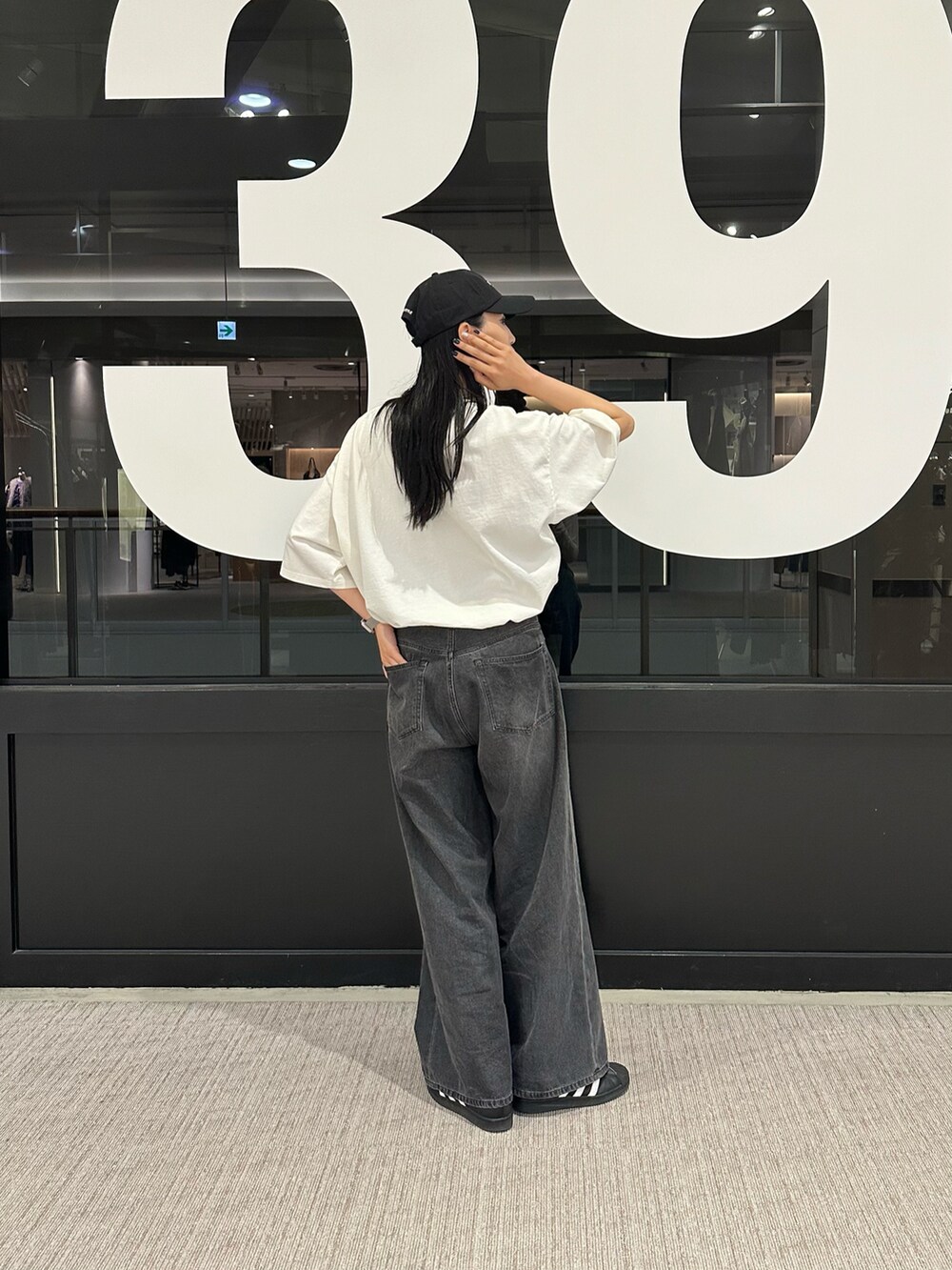 ブラック系のデニムパンツ、ホワイト系のTシャツ/カットソー、ブラック系のキャップを着用したレディースの春コーディネートの3枚目の写真