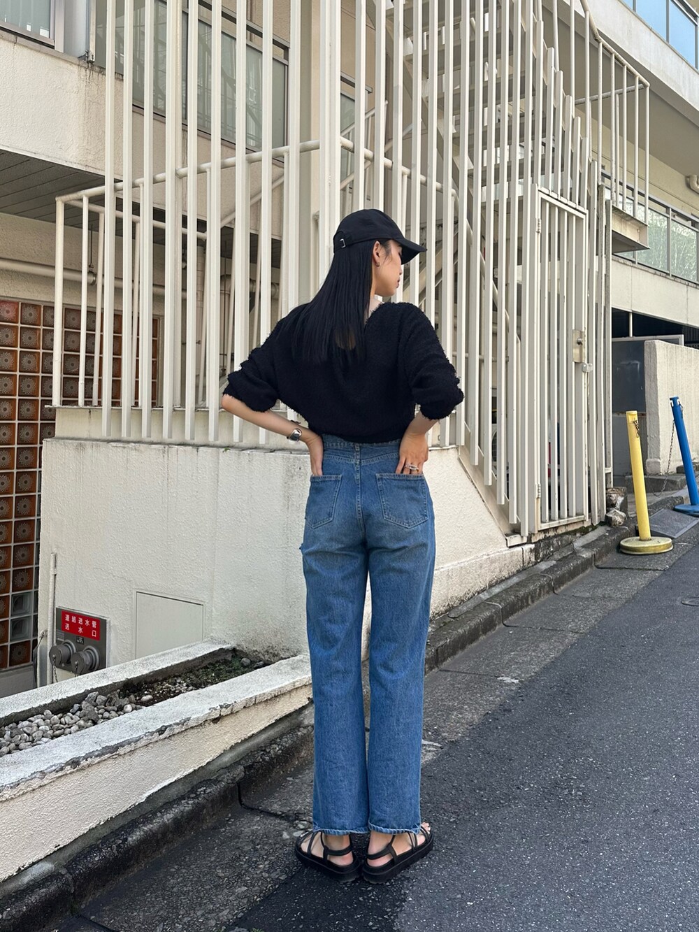 ブルー系のデニムパンツ、ブラック系のアンサンブル、ブラック系のサンダルを着用したレディースの春コーディネートの3枚目の写真