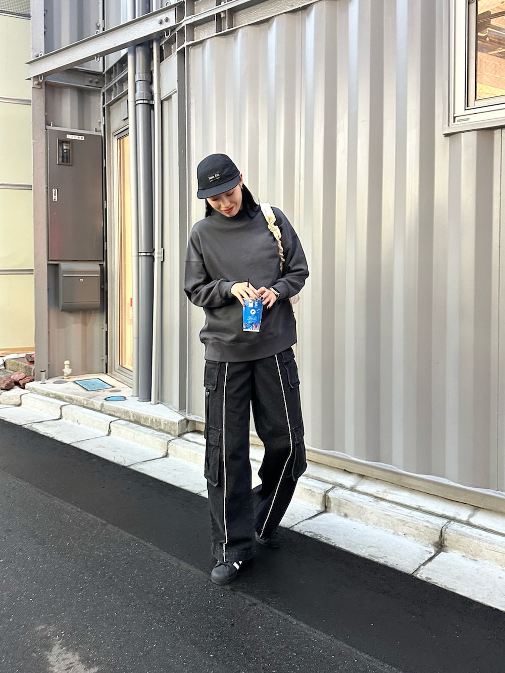 ブラック系のスウェット、ブラック系のデニムパンツ、ホワイト系のショルダーバッグを着用したレディースの冬コーディネートの2枚目の写真