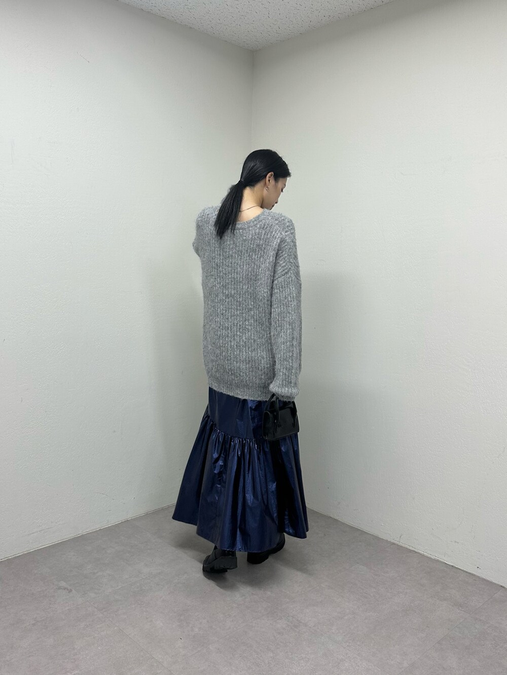 ブルー系のスカート、ブラック系のブーツ、ブラック系のショルダーバッグを着用したレディースの秋コーディネートの4枚目の写真