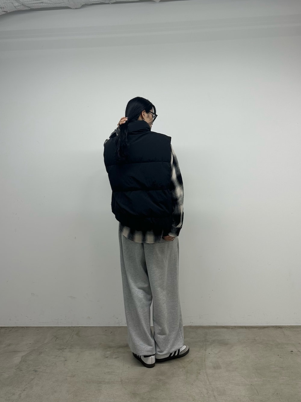 グレー系のスウェットパンツ、ブラック系のダウンベスト、ブラック系のトップスを着用したレディースの秋コーディネートの3枚目の写真