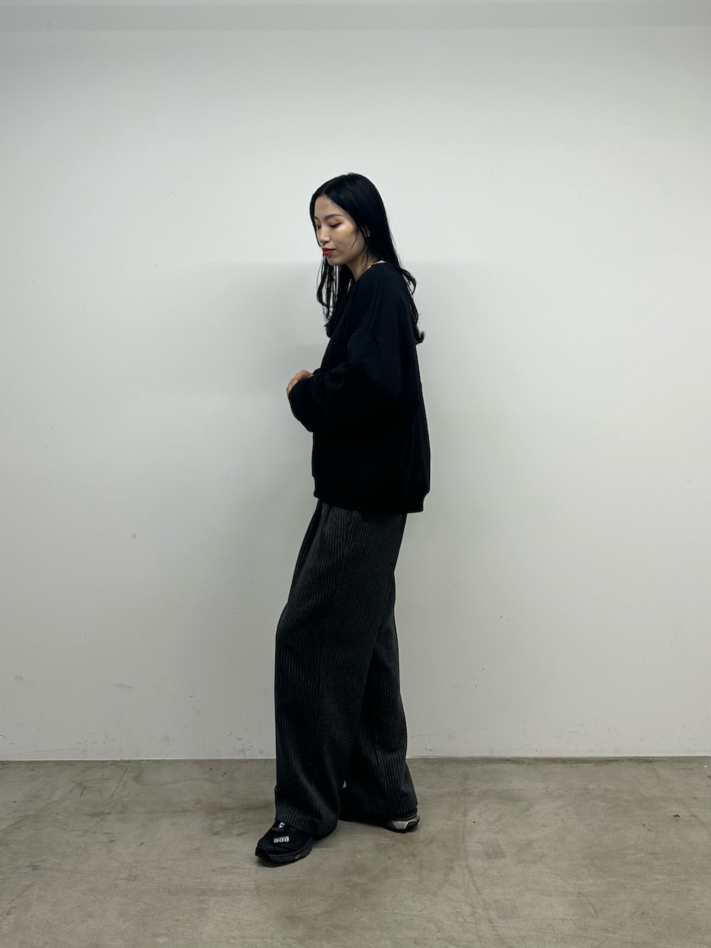 グレー系のスラックス、ブラック系のスウェットを着用したレディースの秋コーディネートの2枚目の写真