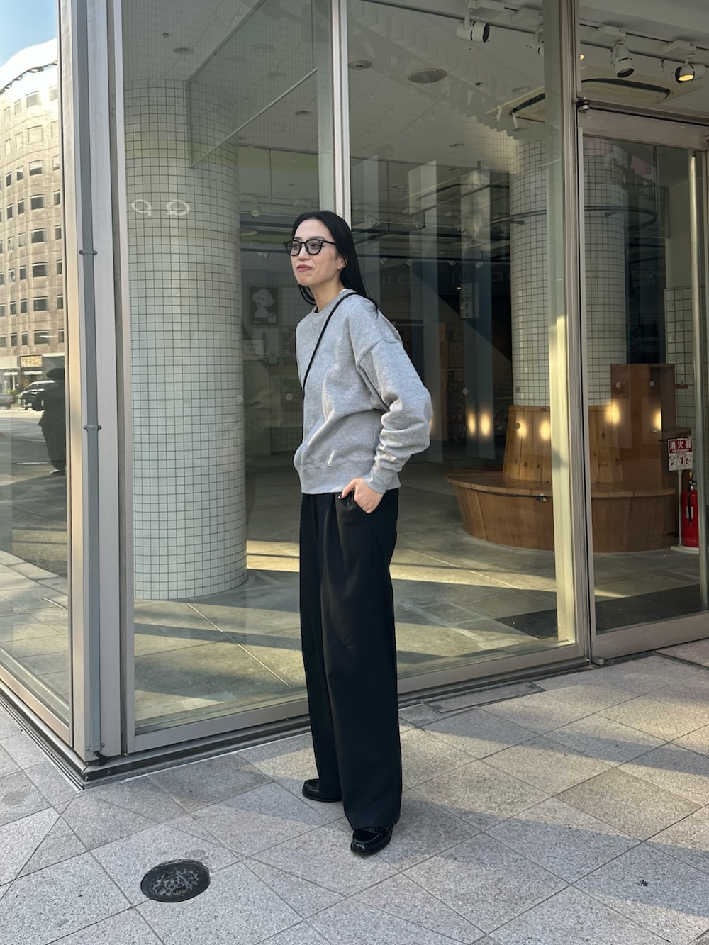 グレー系のスウェット、ブラック系のスラックス、ブラック系のローファーを着用したレディースの冬コーディネートの3枚目の写真