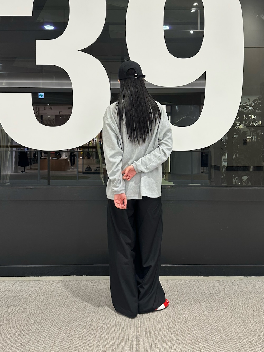 グレー系のTシャツ/カットソー、ブラック系のスラックス、ブラック系のキャップを着用したレディースの春コーディネートの3枚目の写真